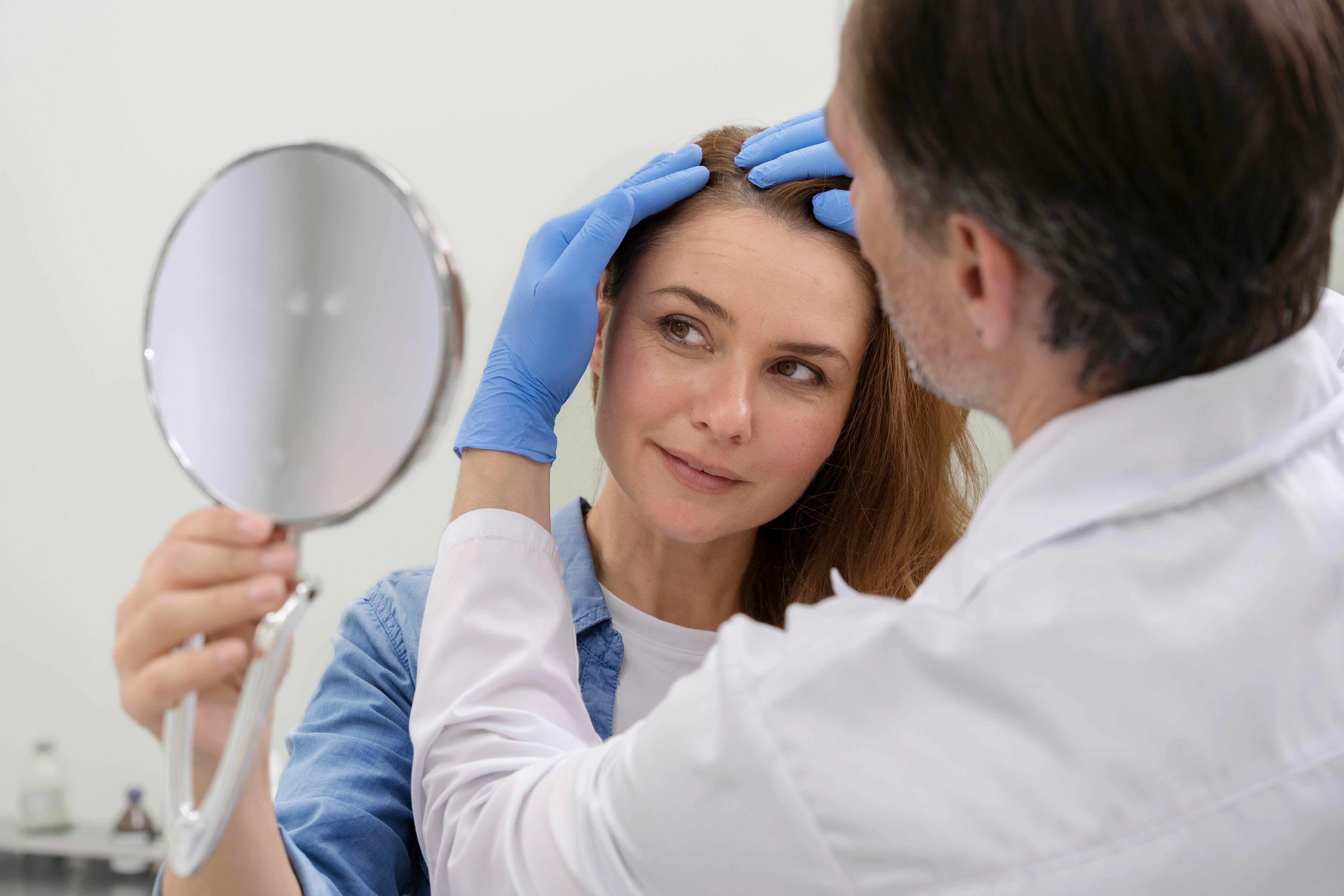 doctor inspecting womens hair line during consultation